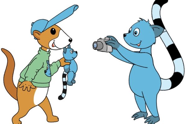 Illustration eines Erdmännchens, welches einen grünen Pullover und eine blaue Schirmmütze trägt. In der Hand hält es einen blauen Plüschtier-Lemur. Ihm gegenüber steht ein blauer Lemur und fotografiert es mit einer Kamera.