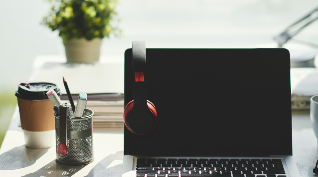 Schreibtisch mit Laptop, Schreibutensilien und Kaffeebecher