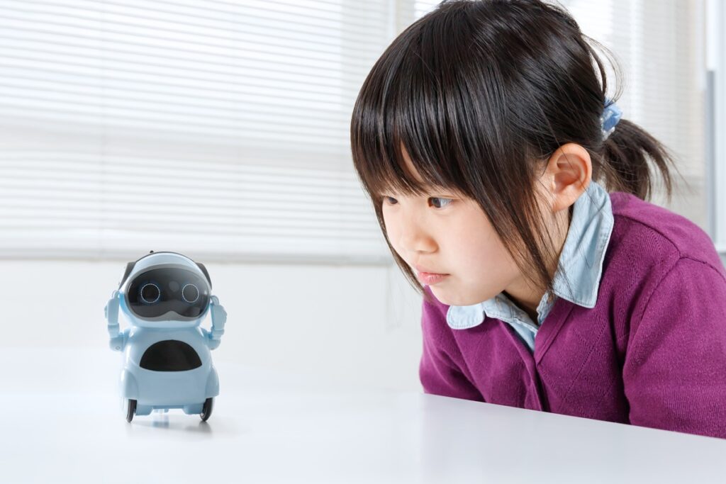 Kind aus Japan hat konzentriert die Augen auf den Bildschirm seines kleinen KI-Tutors gerichtet.