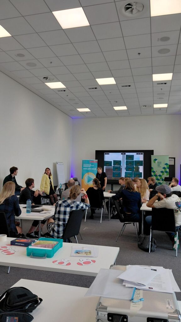 Workshop-Teilnehmende hören einem Vortrag zu und beteiligen sich durch Gespräche am Workshop